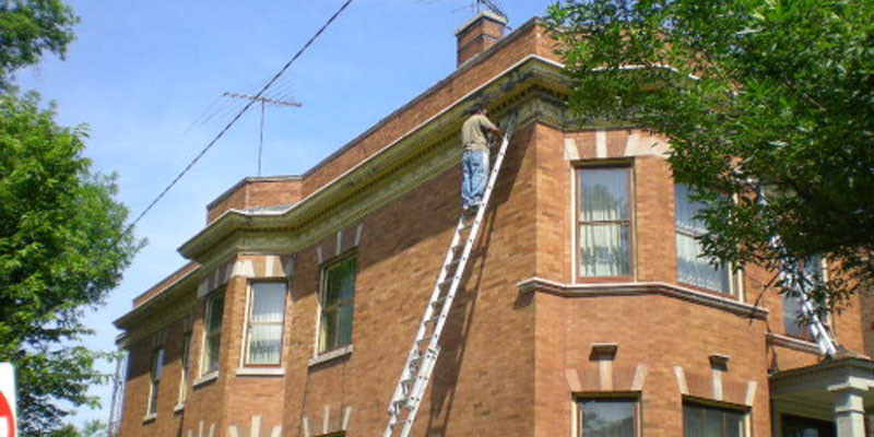 Painting contractor on ladder working on a building's exterior