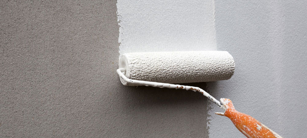 Paint roller applying different shades of paint to an interior wall