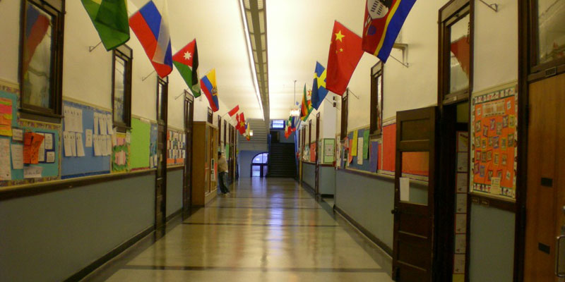 Photo of various country flags lining either side of a school hallway